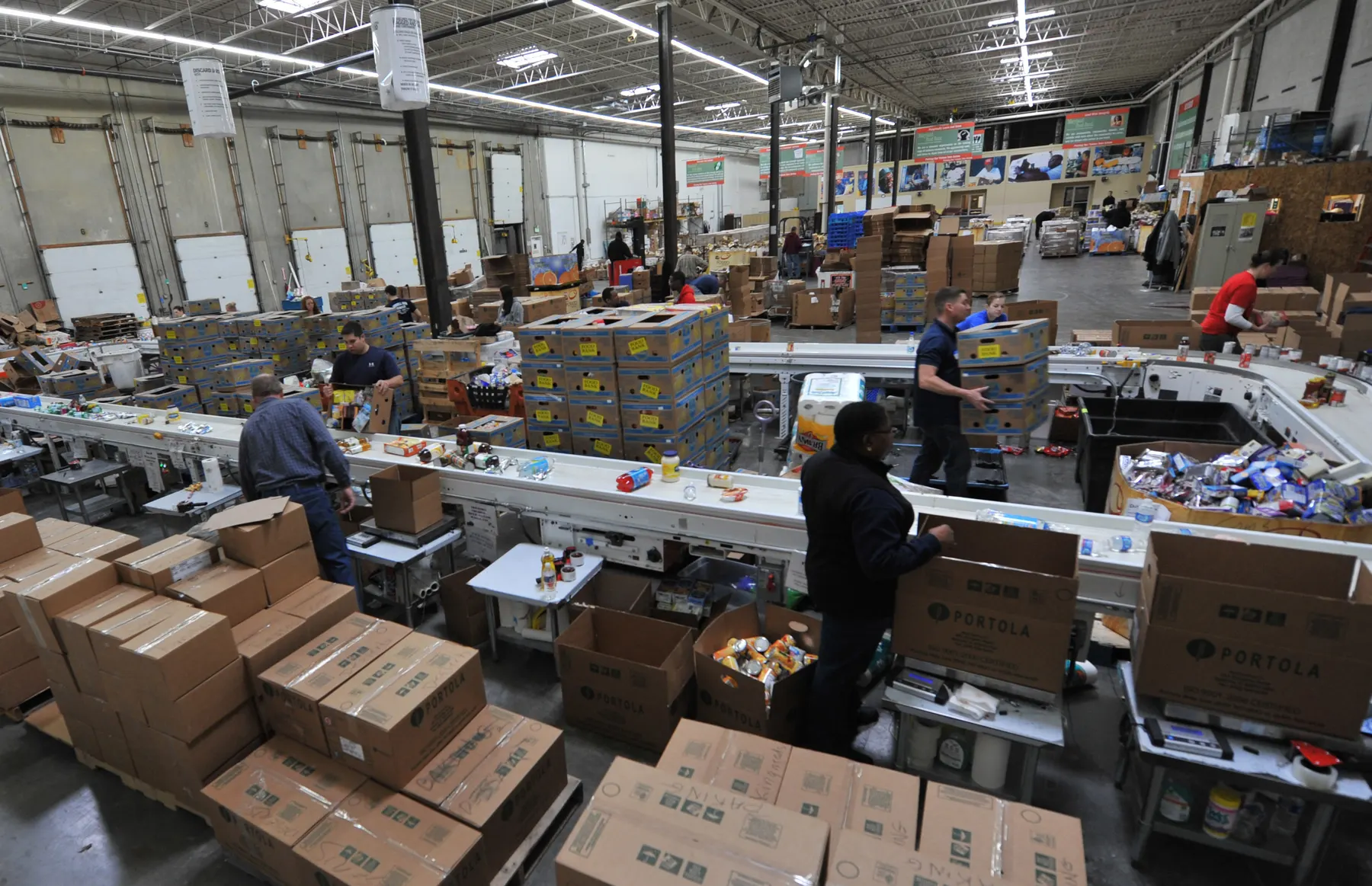 Volunteers sorting donated food into boxes on a long packing line